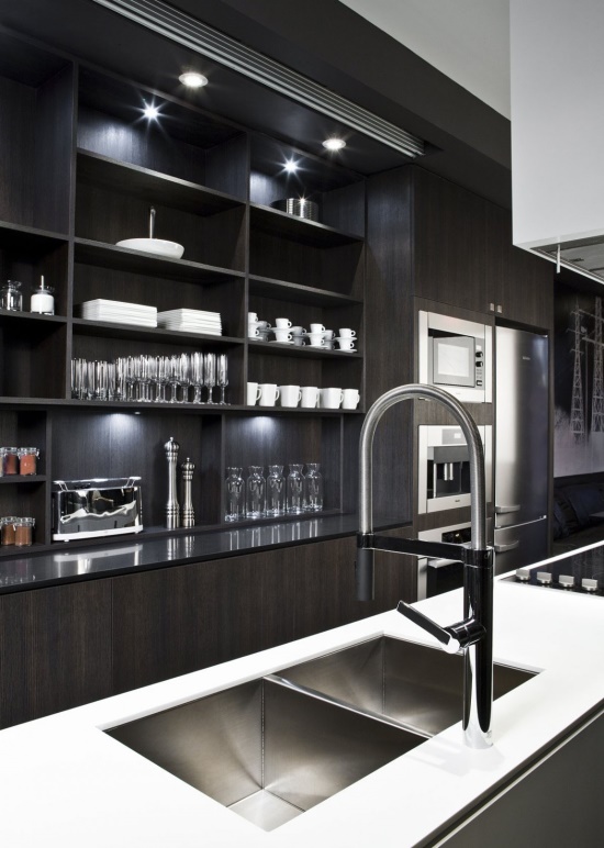 a contemporary dark kitchen with black cabinets, a large white kitchen island, additional lights and stylish faucets