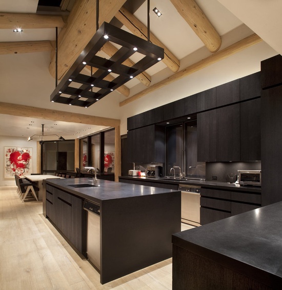 a completely black kitchen with dark cabinets, a sleek backsplash, lights and a lighting frame over the kitchen island