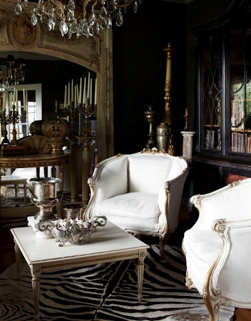 a sophisticated living room with elegant white furniture, an animal skin rug, crystal chandeliers and mirrors