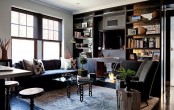 a moody masculine living room with dark furniture, a large storage unit, a glass coffee table and tree stumps