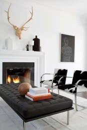 an elegant minimalist living room with a fireplace, a black leather couch, animl print chairs and artworks