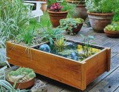 a wooden box mini pond with water plants, a clear ball and a usual planter in the second part
