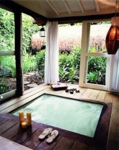 an outdoor-indoor jacuzzi in a small pavilion with sliding doors and a gorgeous garden view – as if you are bathing in the garden