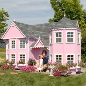 a light pink kids’ playhouse with two floors and pink blooms planted around is a whole real mansion for a little kid