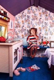 a colorful kids’ playhouse with a purple ceiling, a bright blue floor, a neutral kitchen and a dining table with a checked tablecloth