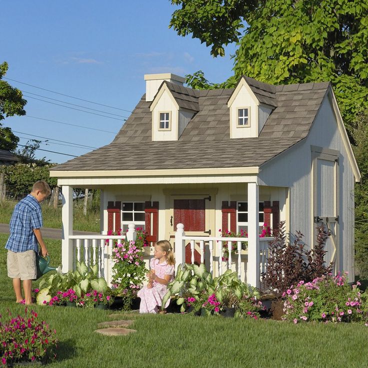 A fairytale like kids' playhouse with a small porch, greenery and blooms planted around is a gorgeous idea