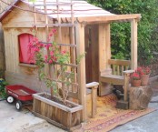 a stained kids’ playhouse with potted blooms, with colorful curtains looks very rustic and very cozy, with rustic stuff around it