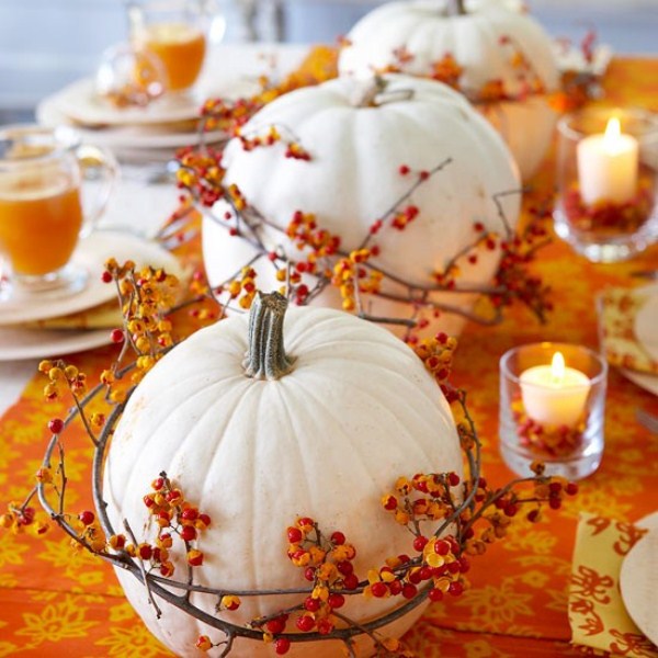 White pumpkins encircled by bittersweet vine and surrounded by candles make a perfect arrangement on an orange table runner.