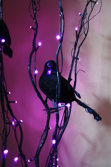 black branches with purple lights and blackbirds is a very cool and bold idea for Halloween, you can easily DIY such stylish decor