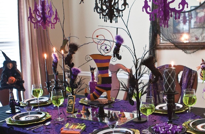 A super bright green, purple, black and orange Halloween tablescape with witches' legs, hats and other catchy decor