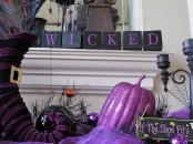 purple and black Halloween table decor with witches’ legs, pumpkins, candles, spiders and WICKED letters