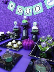 a bright purple, green and black Halloween sweets table with a glitter pumpkin, spiderwebs and various monsters is a very creative and fun idea for a kids’ Halloween party