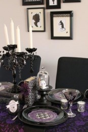 a sophisticated black, white and purple Halloween tablescape with a black candelabra, white candles, skulls, glasses and other stuff