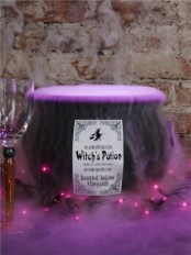 a witches’ cauldron with purple smoke and lights is a chic and cool Halloween decoration that is out of the box