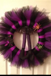 a black and purple striped Halloween wreath with glitter spiders and witches’ legs is a very cool and bold idea for Halloween