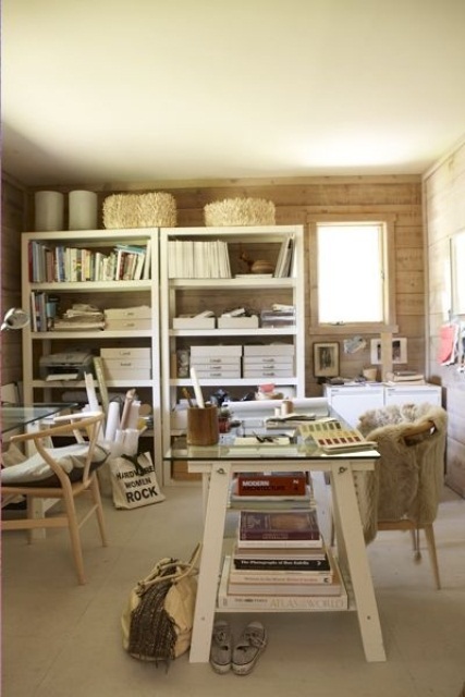 a cozy rustic home office in neutrals, with a white shelving unit and desk, a glass desk and wooden chairs