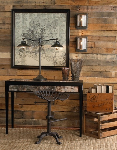 a rustic industrial home office with rough wooden walls, some industrial lamps and an artwork plus a metal chair