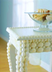 a refined vintage table clad with white seashells is a lovely idea for a beach or coastal space