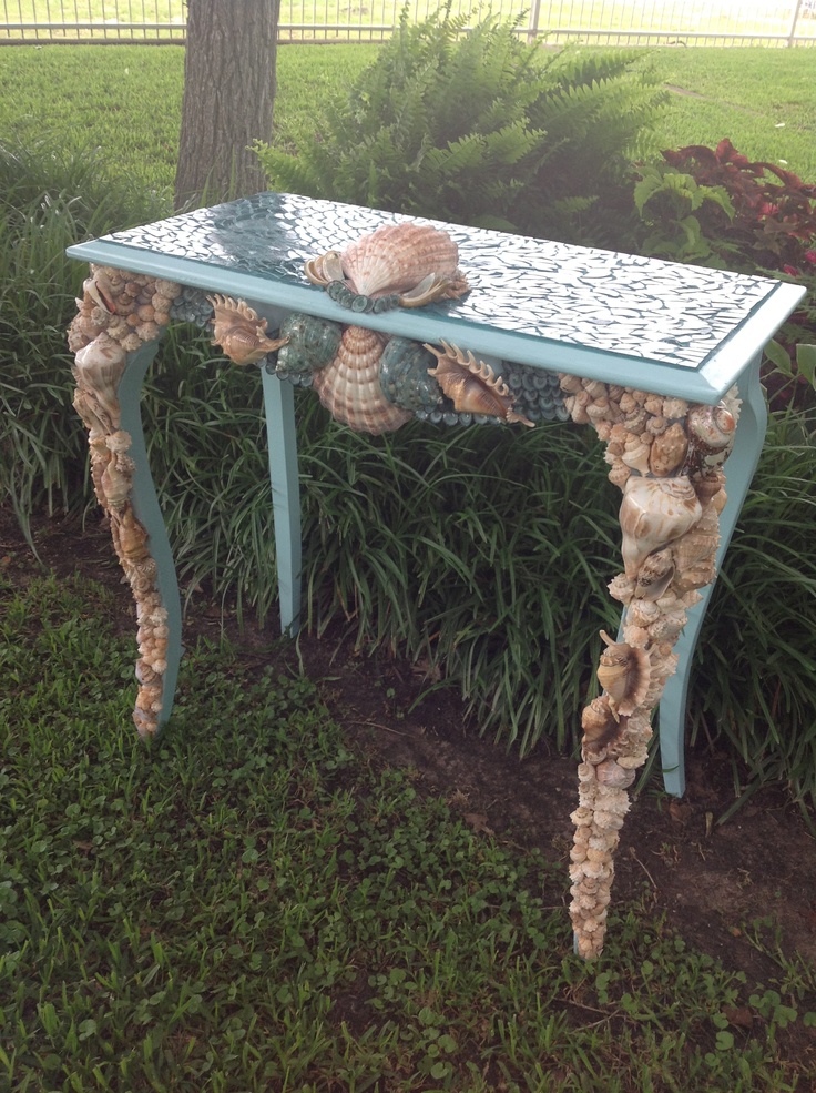 A blue vintage console table clad with seashells looks very sea inspired and very bold