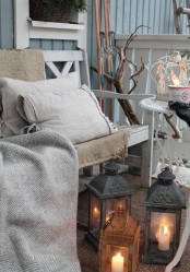 a small rustic terrace with whitewashed vintage furniture, candle lanterns, branches and skis