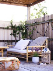 a small boho terrace with candle lanterns, rattan furniture, potted greenery and blooms plus lights