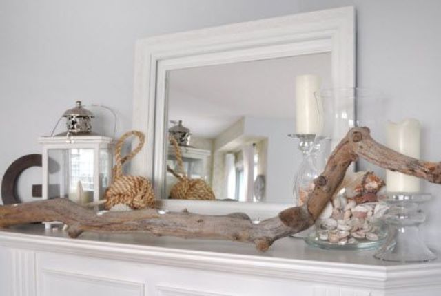A beachy summer mantel with candles, lanterns, driftwood, rope and a large jar with shells