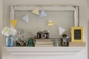 a vintage summer mantel with vintage cameras, books, a colorful bunting, blooms and a framed sign