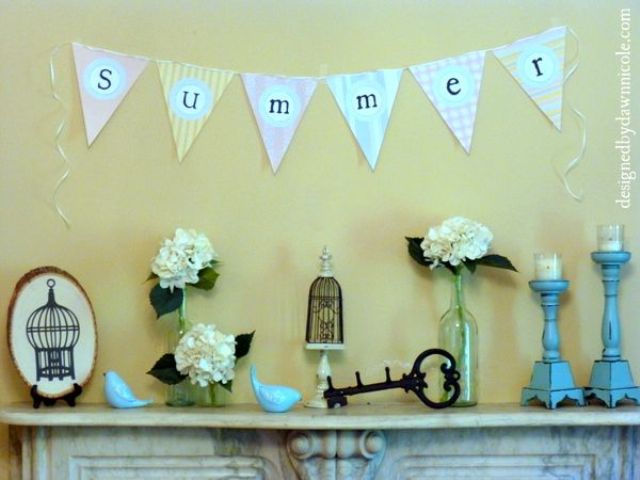A vintage summer mantel with candles, blooms in vases, a banner, vintage keys and cage decor
