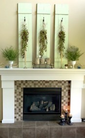 a green summer mantel with green planks with greenery cascading, potted greenery, planters and candles