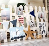 a summer mantel with a beachy feel – a white fence, nautical garlands, starfish and family photos from the holiday