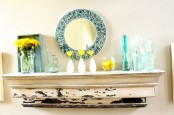 a bright summer mantel done in blue and yellow, with turquoise bottles and vases, yellow blooms and citrus plus a blue mirror