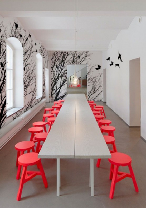 a contemporary dining room in off-white, with red stools and a catchy black birds wall mural to make a statement
