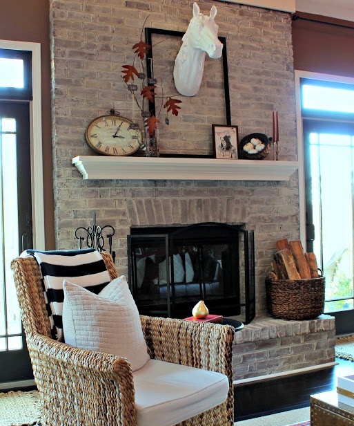 a whitewashed fireplace with a small manter with rustic decor and a basket with firewood next to it