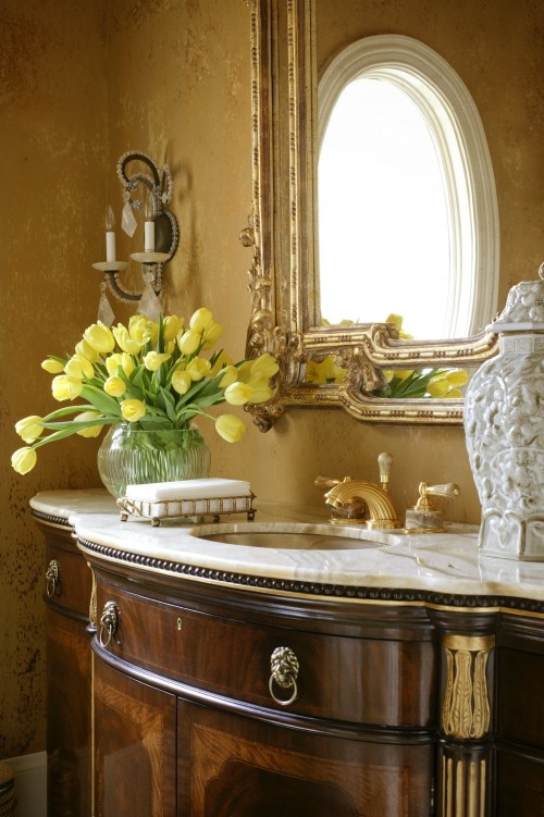 a vintage bathroom with refined furniture and a mirror plus bold blooms in a vase to make it feel fresh and modern