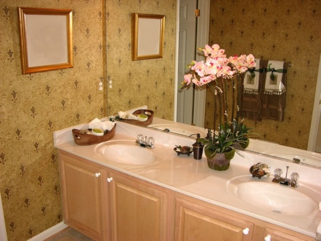 A neutral refined bathroom with wallpaper and a pretty pink orchid on the vanity to make it more chic and luxurious