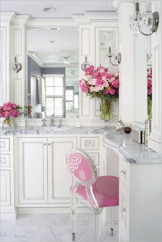 bold pink blooms in vases and a matching chair in pink refresh and spice up the bathroom done in white and neutrals