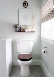 a small neutral bathroom with a half wall that divides the toilet from the rest of the space and neutral shades
