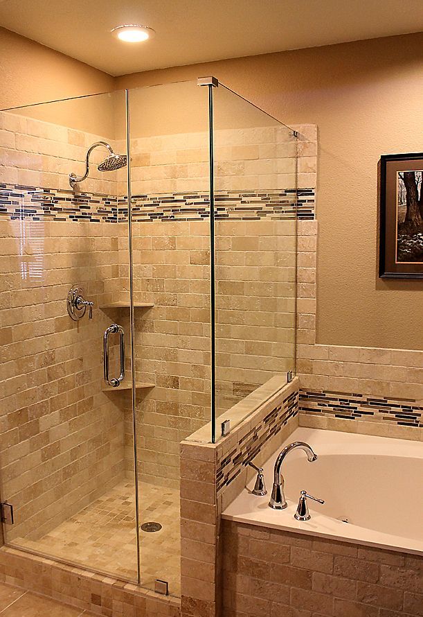 A neutral warm colored bathroom clad with various tiles, with a pony wall in the shower and a bathtub next to it
