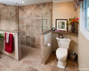 a lvoely warm-colored bathroom with half walls to separate the shower fomr the space and some blooms and an artwork