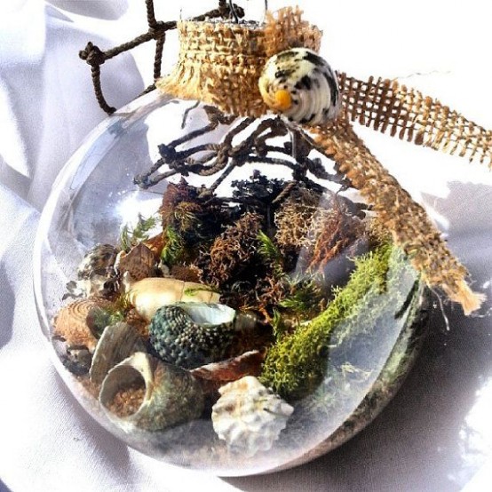 a sea scene in a clear glass Christmas ornament with moss, algae, seashells, beach sand and some burlap