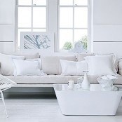 a white Nordic living room with a sofa, a white metal chair and a coffee table with a mirror tabletop is a lovely space to be in