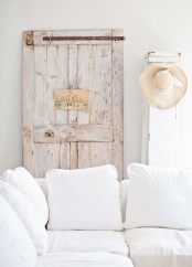 a white sofa, a whitewashed door, a hat and a sign make the space stylish and very soothing