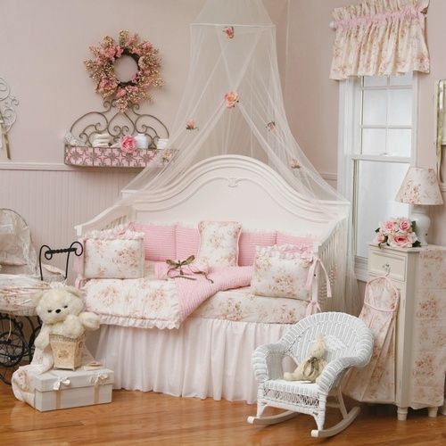 a pink and white shabby chic kid's room with white furniture, floral bedding and curtains, pink touches and cute toys