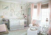 a shabby chic nursery with dove grey walls, pink textiles and pink touches, a gallery wall of empty frames and elegant furniture