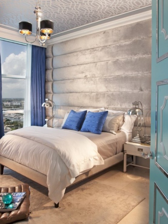 a light grey and silver bedroom infused with bold blue - pillows and curtains of this shade