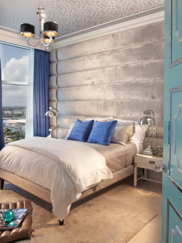 A light grey and silver bedroom infused with bold blue   pillows and curtains of this shade