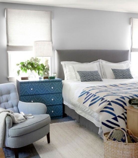 a bedroom in the shades of light grey, a bold patterned sideboard and grey and blue bedding
