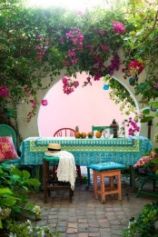 a colorful boho dining space with greenery and bold blooms, a table with a bright tablecloth and bold textiles