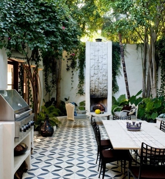 an eclectic patio with a mosaic tile floor, wood and metal furniture, a fireplace and a hearth for cooking
