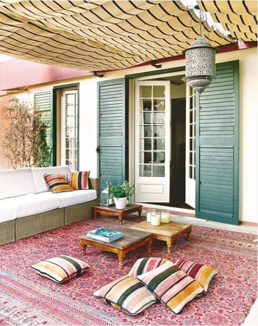 a simple and bright boho patio with striped pillows, low wooden tables, a Moroccan lantern